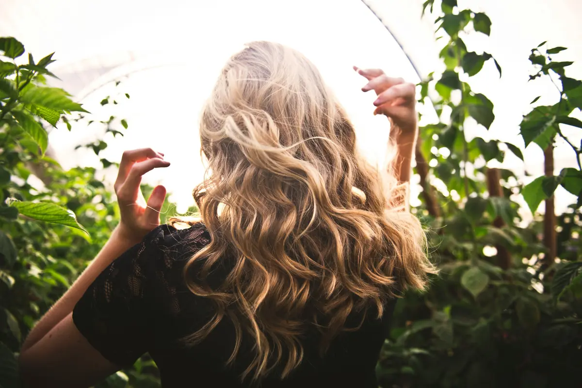 Blondierte Haare pflegen: Frau mit langen, gesund glänzenden, gewellten blonden Haaren